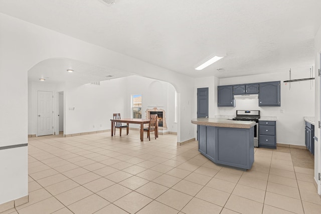 10504 W Connemara Ave SW, Albuquerque, NM 87121 - kitchen featuring gas range, arched walkways, under cabinet range hood, light tile patterned floors, and light countertops