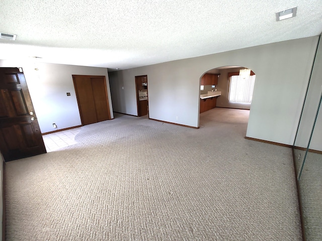 4111 El Cajon Ct SE, Rio Rancho, NM 87124 - spare room with baseboards, arched walkways, a textured ceiling, and light colored carpet