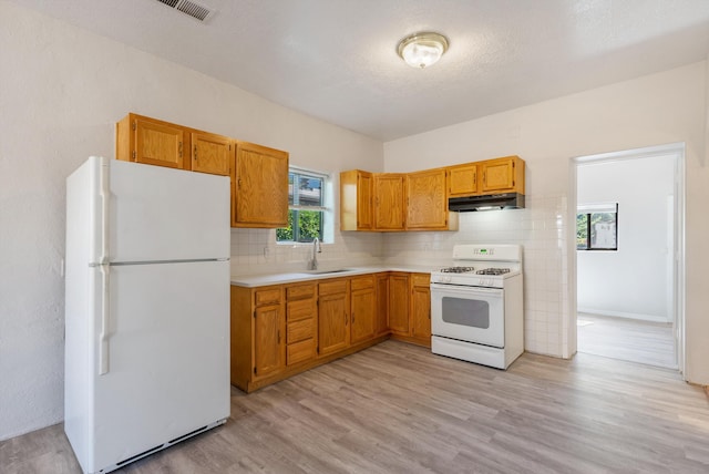 2012 Foothill Dr SW, Albuquerque, NM 87105 - kitchen with white appliances, a sink, under cabinet range hood, light countertops, and light wood-style floors
