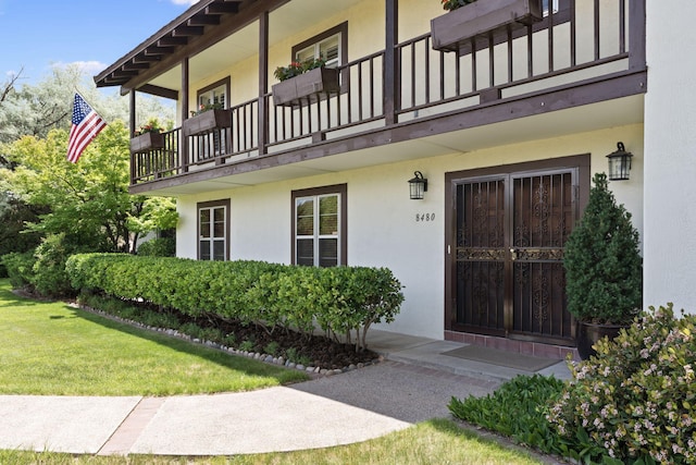 8480 Osuna Rd NE, Albuquerque, NM 87111 - view of exterior entry with a balcony, stucco siding, and a yard