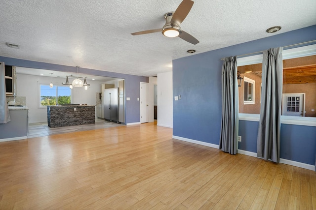 4509 Tottle Ave NW, Albuquerque, NM 87114 - unfurnished living room featuring a ceiling fan, light wood-type flooring, a textured ceiling, a chandelier, and baseboards