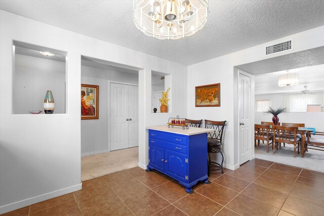 1951 Corta Rustica, Los Lunas, NM 87031 - kitchen featuring blue cabinetry, a chandelier, a textured ceiling, light countertops, and dark tile patterned floors
