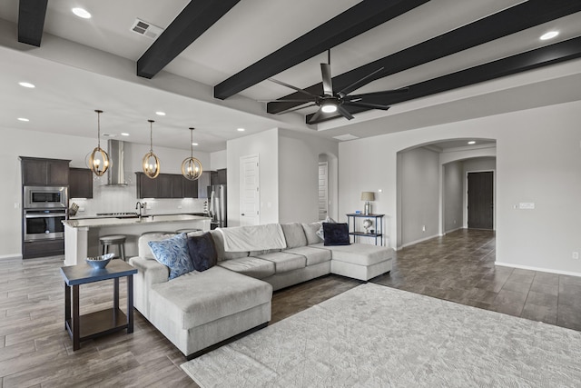 6969 Cleary Loop NE, Rio Rancho, NM 87144 - living room with arched walkways, recessed lighting, dark wood-type flooring, beam ceiling, and baseboards