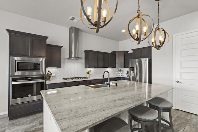 6969 Cleary Loop NE, Rio Rancho, NM 87144 - kitchen featuring appliances with stainless steel finishes, wall chimney exhaust hood, a chandelier, a sink, and backsplash
