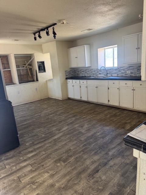 1212 W Reinken Ave, Belen, NM 87002 - kitchen with white cabinets, dark wood-style flooring, rail lighting, and dark countertops