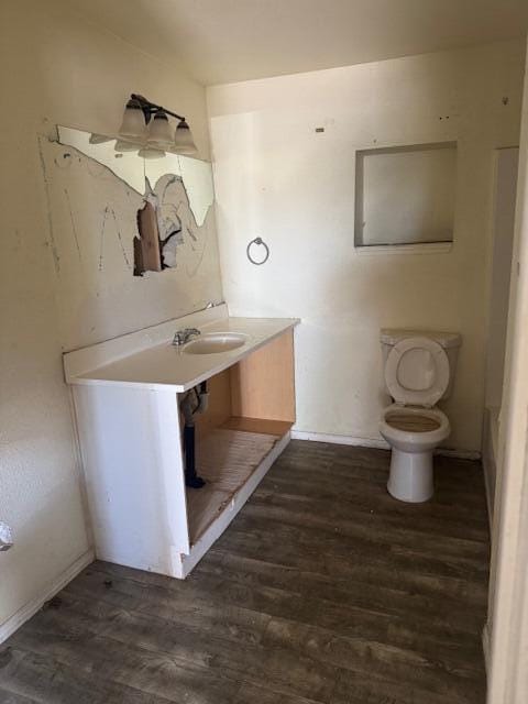 1212 W Reinken Ave, Belen, NM 87002 - bathroom featuring wood finished floors, toilet, a sink, and baseboards