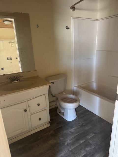 1212 W Reinken Ave, Belen, NM 87002 - bathroom featuring toilet, vanity, bathing tub / shower combination, and wood finished floors