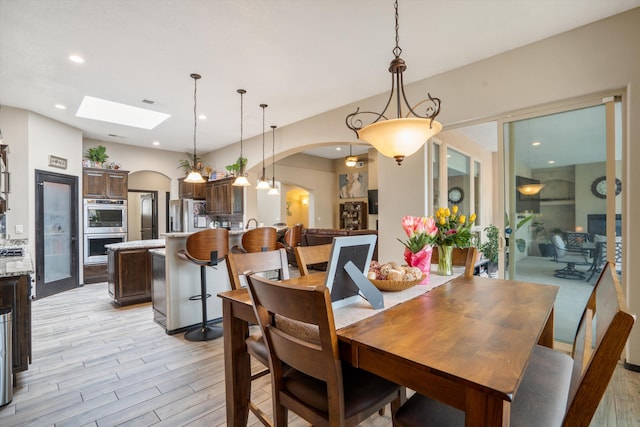 405 Holt Ct NE, Rio Rancho, NM 87124 - dining area with arched walkways, a skylight, light wood-style flooring, and recessed lighting