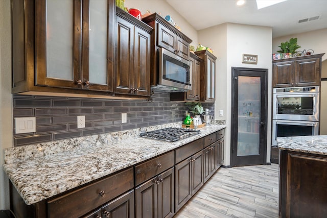 405 Holt Ct NE, Rio Rancho, NM 87124 - kitchen featuring appliances with stainless steel finishes, dark brown cabinets, decorative backsplash, light stone countertops, and recessed lighting