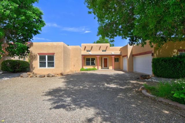 2705 Pueblo Grande Trl NW, Albuquerque, NM 87120 - pueblo revival-style home with a garage, stucco siding, and driveway