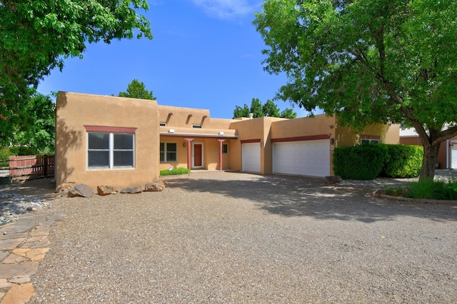 2705 Pueblo Grande Trl NW, Albuquerque, NM 87120 - pueblo revival-style home with an attached garage, stucco siding, and driveway