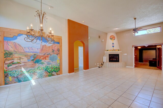 2705 Pueblo Grande Trl NW, Albuquerque, NM 87120 - unfurnished living room with a ceiling fan, light tile patterned flooring, a tiled fireplace, a chandelier, and arched walkways