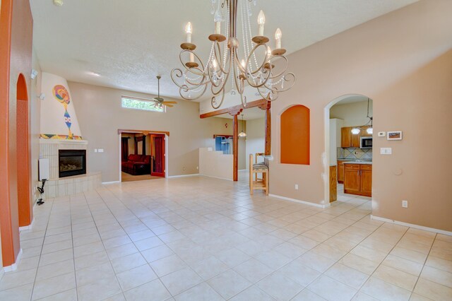2705 Pueblo Grande Trl NW, Albuquerque, NM 87120 - unfurnished living room featuring a ceiling fan, light tile patterned floors, a tiled fireplace, arched walkways, and a chandelier