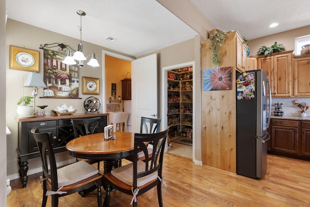 4210 Agave Ct SW, Los Lunas, NM 87031 - dining area with a textured ceiling, a chandelier, and light wood finished floors