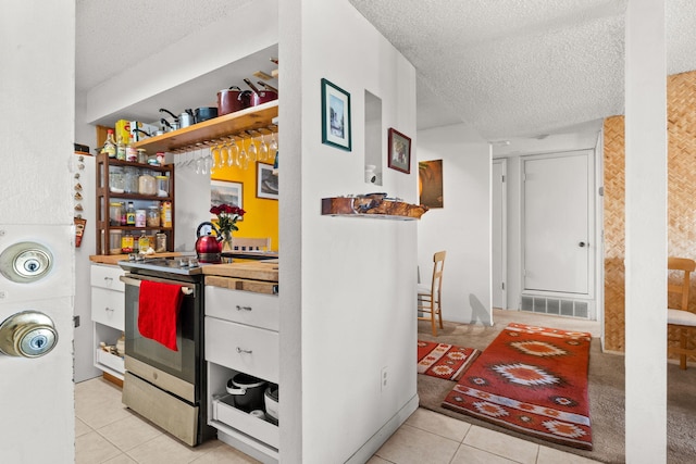 3867 Montgomery Blvd NE Unit 1633, Albuquerque, NM 87109 - kitchen featuring stainless steel electric range oven, a textured ceiling, light tile patterned floors, white cabinets, and open shelves