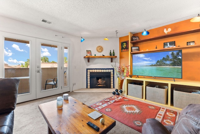 3867 Montgomery Blvd NE Unit 1633, Albuquerque, NM 87109 - living room featuring carpet, a textured ceiling, french doors, and a tiled fireplace