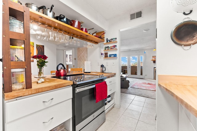 3867 Montgomery Blvd NE Unit 1633, Albuquerque, NM 87109 - kitchen featuring stainless steel electric range oven, butcher block counters, open shelves, white cabinetry, and a textured ceiling