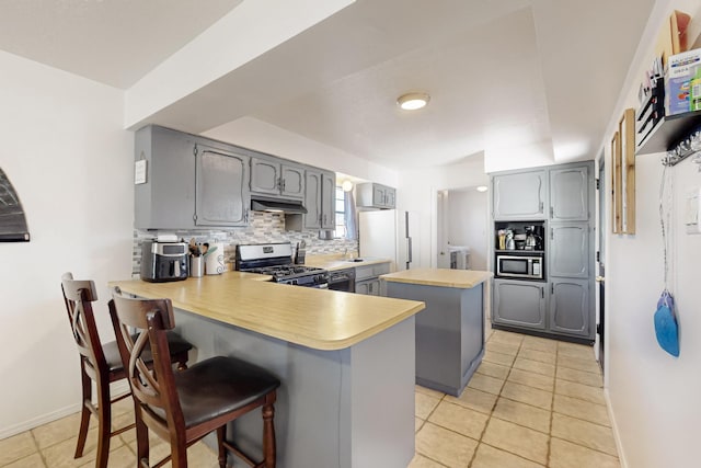 648 Frederico Blvd, Rio Communities, NM 87002 - kitchen featuring appliances with stainless steel finishes, gray cabinetry, a peninsula, under cabinet range hood, and a center island