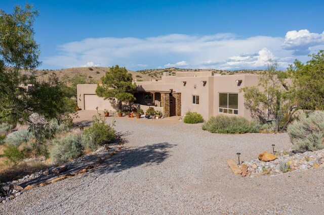 1 Seasons Cir, Placitas, NM 87043 - pueblo revival-style home featuring stucco siding, a garage, and driveway