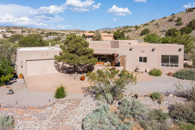 1 Seasons Cir, Placitas, NM 87043 - pueblo-style house featuring stucco siding, an attached garage, driveway, and a mountain view
