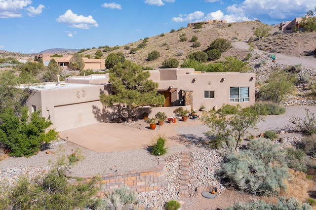 1 Seasons Cir, Placitas, NM 87043 - view of front facade featuring stucco siding, a mountain view, driveway, and an attached garage