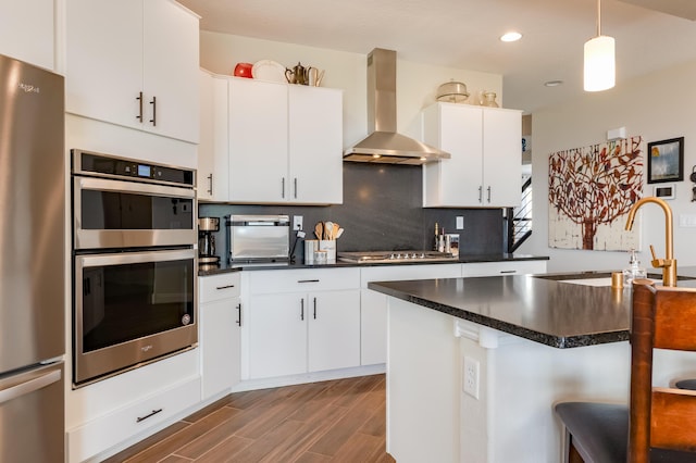 1608 Mammoth Way, Albuquerque, NM 87120 - kitchen with wall chimney exhaust hood, stainless steel appliances, dark countertops, dark wood-style flooring, and tasteful backsplash