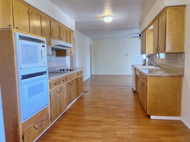 10008 Greene Ave NW, Albuquerque, NM 87114 - kitchen featuring white appliances, under cabinet range hood, a sink, tasteful backsplash, and light wood finished floors