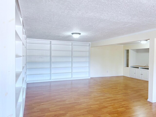 10008 Greene Ave NW, Albuquerque, NM 87114 - empty room with light wood-style flooring, a textured ceiling, and built in shelves