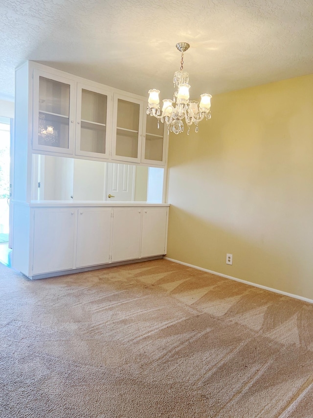 10008 Greene Ave NW, Albuquerque, NM 87114 - empty room with light carpet, a chandelier, baseboards, and a textured ceiling