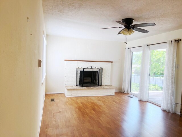 10008 Greene Ave NW, Albuquerque, NM 87114 - unfurnished living room with a textured ceiling, wood finished floors, a ceiling fan, a brick fireplace, and baseboards