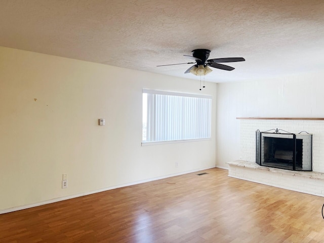 10008 Greene Ave NW, Albuquerque, NM 87114 - unfurnished living room with wood finished floors, ceiling fan, a textured ceiling, a brick fireplace, and baseboards
