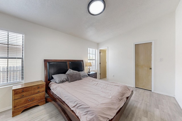 1128 Pandora Dr SW, Los Lunas, NM 87031 - bedroom with light wood-type flooring, lofted ceiling, baseboards, and a textured ceiling