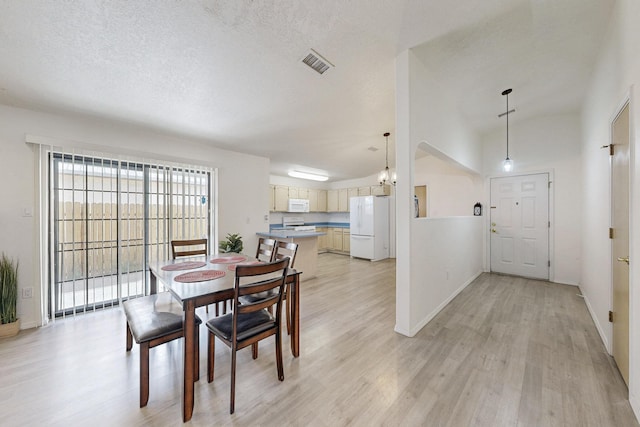1128 Pandora Dr SW, Los Lunas, NM 87031 - dining area featuring light wood-type flooring, lofted ceiling, baseboards, and a textured ceiling