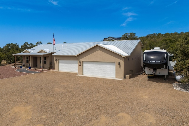 31 Express Blvd, Sandia Park, NM 87047 - view of front of property with a garage, driveway, metal roof, stucco siding, and covered porch