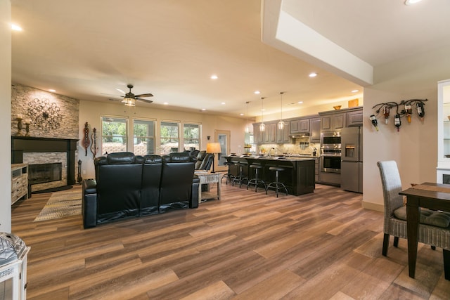 31 Express Blvd, Sandia Park, NM 87047 - living room with wood finished floors, a ceiling fan, a stone fireplace, and recessed lighting