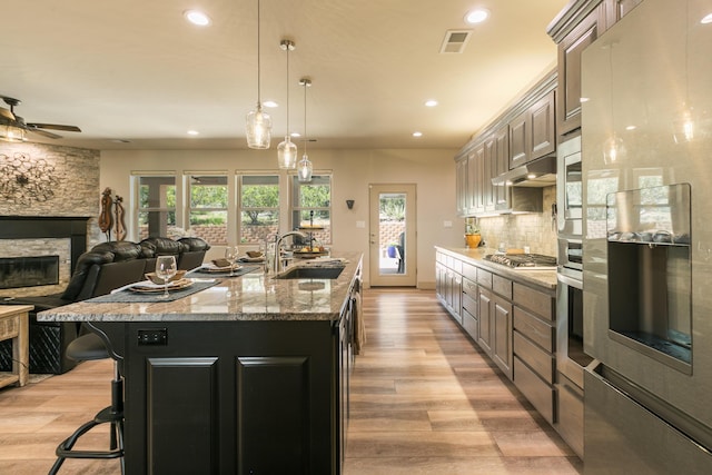 31 Express Blvd, Sandia Park, NM 87047 - kitchen with stainless steel appliances, a sink, recessed lighting, light wood finished floors, and a fireplace