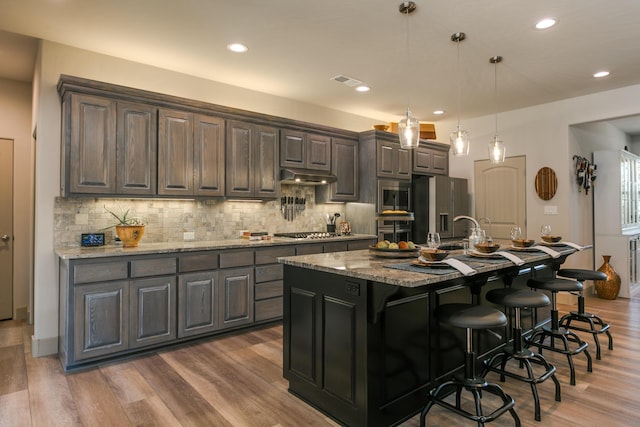 31 Express Blvd, Sandia Park, NM 87047 - kitchen with stainless steel appliances, under cabinet range hood, tasteful backsplash, a kitchen breakfast bar, and recessed lighting