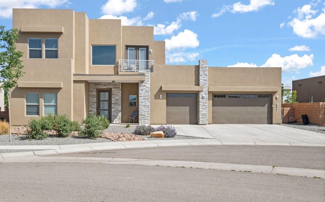 6527 Trestle Glen Rd NW, Albuquerque, NM 87120 - view of front facade featuring a balcony, stucco siding, stone siding, an attached garage, and concrete driveway