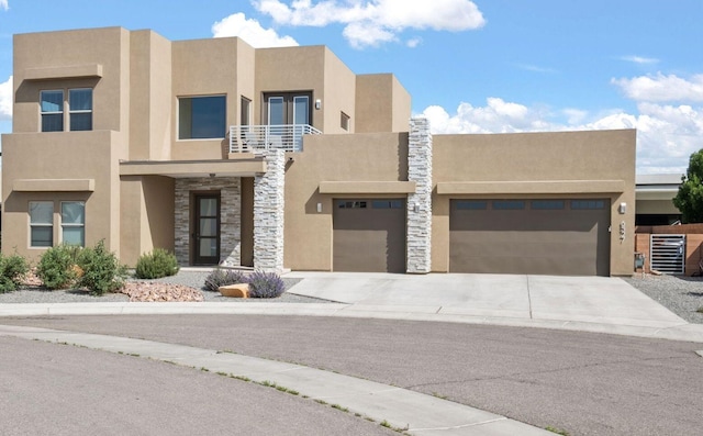 6527 Trestle Glen Rd NW, Albuquerque, NM 87120 - view of front of property with stucco siding, stone siding, a balcony, concrete driveway, and an attached garage