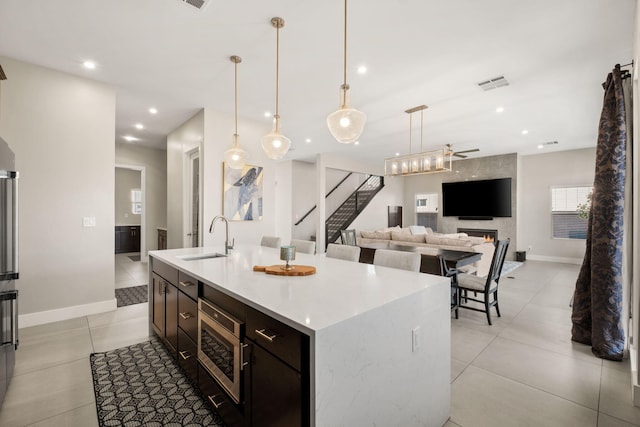6527 Trestle Glen Rd NW, Albuquerque, NM 87120 - kitchen with stainless steel microwave, light tile patterned floors, an island with sink, decorative light fixtures, and recessed lighting