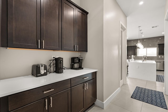 6527 Trestle Glen Rd NW, Albuquerque, NM 87120 - kitchen with dark brown cabinetry, light countertops, light tile patterned floors, baseboards, and stainless steel dishwasher