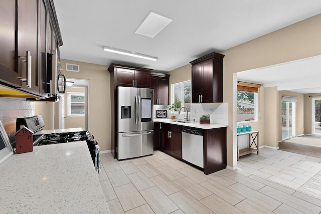3801 Simms Ave SE, Albuquerque, NM 87108 - kitchen with appliances with stainless steel finishes, backsplash, dark brown cabinets, and light stone counters