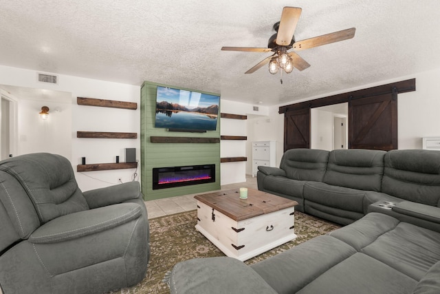 3758 Cattle Dr NE, Rio Rancho, NM 87144 - living room featuring a barn door, a textured ceiling, ceiling fan, a glass covered fireplace, and tile patterned flooring