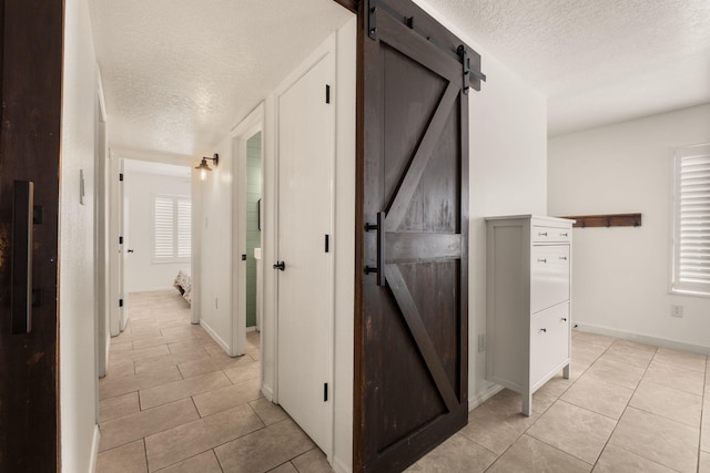 3758 Cattle Dr NE, Rio Rancho, NM 87144 - hallway featuring a barn door, a textured ceiling, and light tile patterned floors