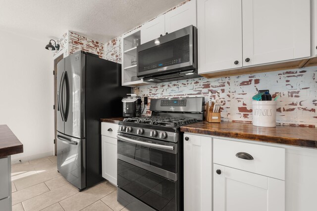 3758 Cattle Dr NE, Rio Rancho, NM 87144 - kitchen featuring appliances with stainless steel finishes, wooden counters, white cabinetry, backsplash, and light tile patterned floors
