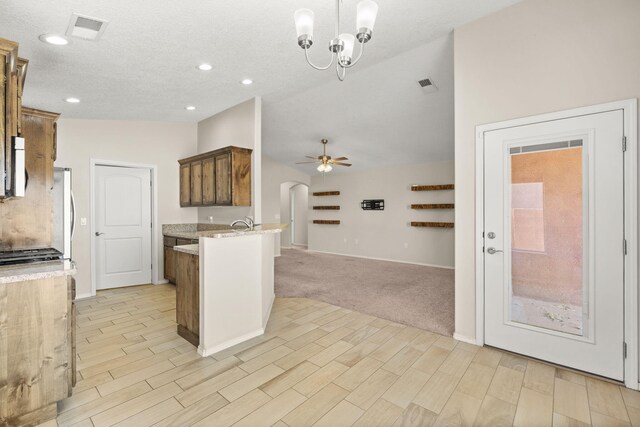 2170 Firewheel Ave SW, Los Lunas, NM 87031 - kitchen with lofted ceiling, a peninsula, light stone counters, ceiling fan, and arched walkways