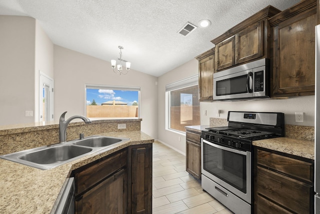 2170 Firewheel Ave SW, Los Lunas, NM 87031 - kitchen with appliances with stainless steel finishes, lofted ceiling, a chandelier, light countertops, and a textured ceiling