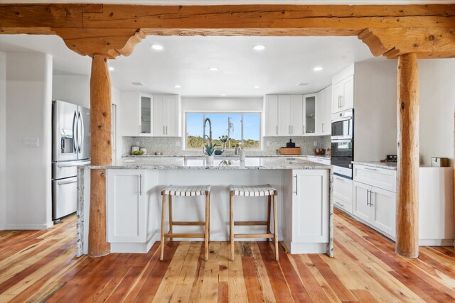 30A Arroyo Coyote Rd, Santa Fe, NM 87508 - kitchen with stainless steel fridge, light wood-style floors, glass insert cabinets, a breakfast bar area, and recessed lighting
