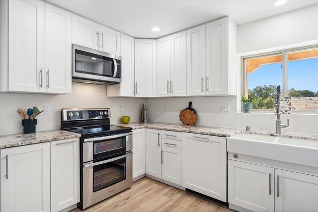 30A Arroyo Coyote Rd, Santa Fe, NM 87508 - kitchen with stainless steel appliances, recessed lighting, white cabinets, and light wood-style floors