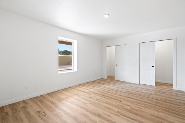 30A Arroyo Coyote Rd, Santa Fe, NM 87508 - unfurnished bedroom featuring light wood-style flooring and two closets
